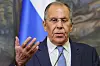 Sergey Lavrov taler foran et russisk flagg og løfter hånden under en pressekonferanse.