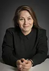 Studioportrett av mezzosopranen Ann-Beth Solvang i svart skjorte med hendene samlet foran seg.
