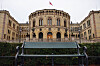 Stortinget i Oslo sett bak en benk, med norsk flagg på taket.