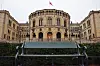 Stortinget i Oslo sett bak en benk, med norsk flagg på taket.