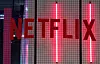 Rød Netflix-logo foran et mørkt, rutemønstret glassparti med vertikale lys.