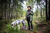 Hans Rustad med hatt på skogstur, med en flekket hund i forgrunnen.