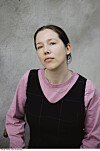 Portrett av Anna Albrigtsen i rosa bluse og svart kjole mot en grå vegg.