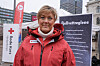 Grete Herlofson i rød Røde Kors-jakke foran en plakat med Fjellvettreglene i Oslo.