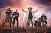 Lasse Stefanz opptrer på scenen med vokalist i hatt, gitarister og trommeslager.