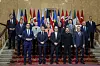 Gruppebilde av europeiske ledere og Ukrainas president foran nasjonalflagg i en utsmykket trapp.
