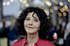 Unni Lindell i rød skjorte foran et festpyntet arrangementslokale i Bergen.
