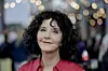 Unni Lindell i rød skjorte foran et festpyntet arrangementslokale i Bergen.