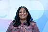 Lubna Jaffery smiler foran en blå bakgrunn under lanseringen av en likestillingsstrategi.