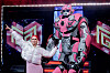 Erika Norwich i sølvfarget antrekk står ved siden av den store robotfiguren Super Rob på en opplyst scene.