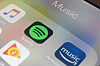 iPhone-skjerm med fargerike ikoner for Spotify, Apple Music og Amazon Music.