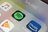 iPhone-skjerm med fargerike ikoner for Spotify, Apple Music og Amazon Music.
