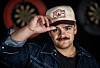 Tobias Sten i dongerijakke og caps foran dartskiver på baren Ly i Oslo.