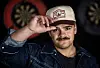 Tobias Sten i dongerijakke og caps foran dartskiver på baren Ly i Oslo.