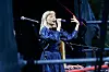 Aurora Aksnes synger i blå scenebelysning med mikrofon og keyboard under en utekonsert.