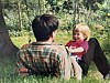Barn smiler på fanget til en voksen i en grønn skog.