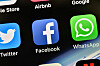 Nærbilde av Facebook- og WhatsApp-ikonene på en iPhone, med flere appikoner rundt.