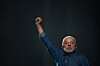 Luiz Inácio Lula da Silva løfter en knyttet neve mot en mørk bakgrunn.