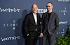 Joachim Trier og Eskil Vogt poserer foran en mørk pressevegg med filmlogoer.