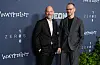 Joachim Trier og Eskil Vogt poserer foran en mørk pressevegg med filmlogoer.