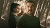 Tre skuespillere står i en mørk skogscene, med Liev Schreiber fremst.