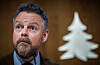 Torbjørn Røe Isaksen taler ved en mikrofon foran Gyldendals hvite trelogo.