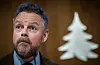 Torbjørn Røe Isaksen taler ved en mikrofon foran Gyldendals hvite trelogo.